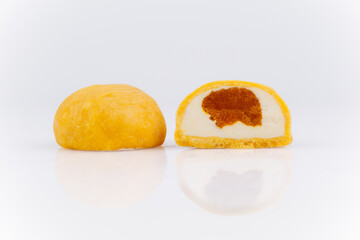 Yellow mochi ice cream cut in half with creamy and caramel center on white background