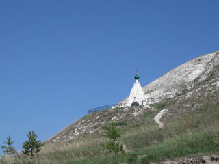 White religious monument on a hill against clear blue sky  