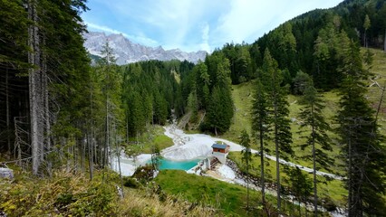 Mountain stream and turquoise water reservoir in an alpine forest, Austria