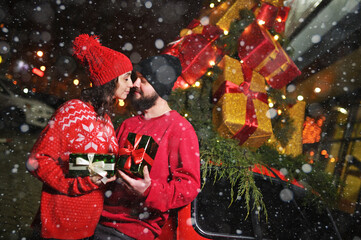 lovers with gifts in their hands kiss against the backdrop of snow and celebrate Valentine's Day