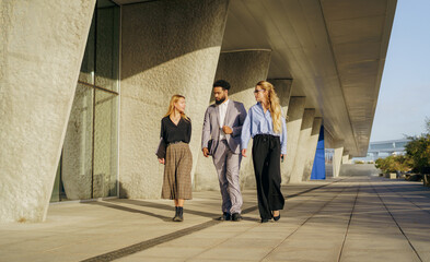A professional group is walking together in a modern urban setting at daytime, enjoying the walk