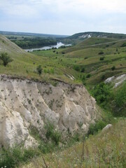 Scenic river valley with rolling hills and lush greenery under cloudy sky  