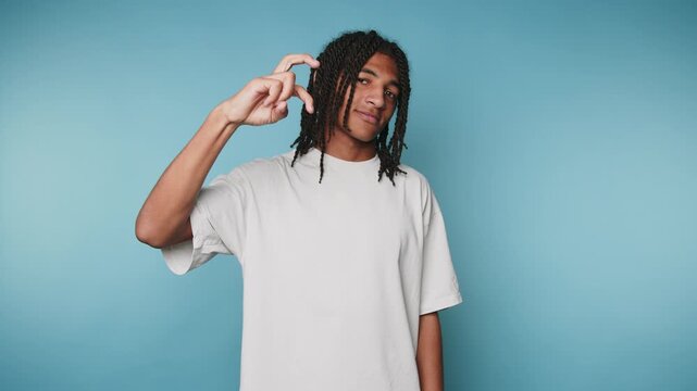 footage of young man gestures something small with his fingers, symbolizing humor and light-heartedness on blue background