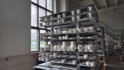 porcelain products on the shelves at the factory, prepared for firing in the kiln. Tableware Making