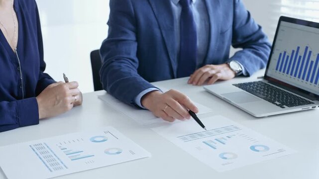 Business professionals reviewing financial data, pointing at laptop charts and shared documents during collaborative strategy session. Business people and finance concept - Powered by Adobe