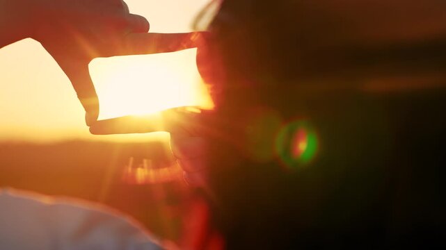 Seeing world differently. Business planning. Girl shows with her fingers frame symbol, sun. Hands of young woman director of photography make gesture in frame, sunset park. Everything is like in movie