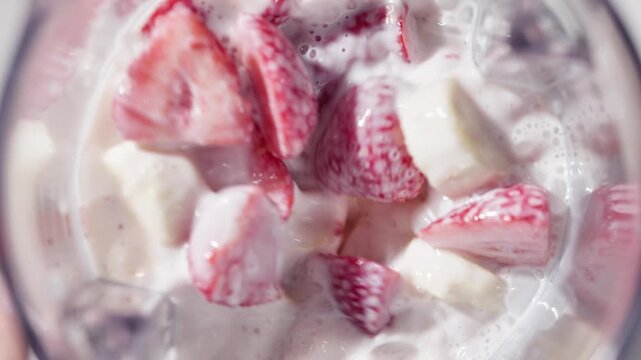 Strawberry and banana pink milkshake blended in blender with splashes. top view. slow motion. Healthy breakfast smoothie drink making , food closeup
