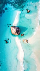 High-angle view of a pristine, turquoise lagoon featuring a white sand spit and unique rock formations, showcasing the beauty of the natural environment.