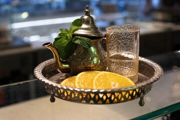 Moroccan tea. Tea in a silver teapot. Next to it stands a glass. Decorated with mint and orange...