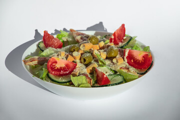 Caesar salad on a white plate with juicy green salad, tomatoes, parmesan, chicken brisket and croutons