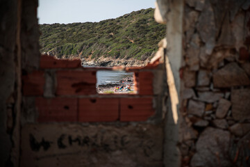 The beach of Villasimius can be seen in a hole in the wall of an abandoned factory