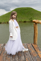 Little girl in a white festive dress in nature.