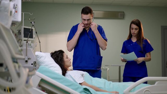 A doctor uses a stethoscope to examine a female patient in a hospital setting.