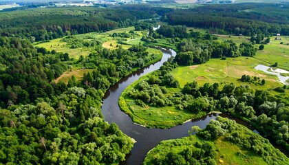 Aerial shot of a winding river carving through a lush, green landscape with forests and meadows