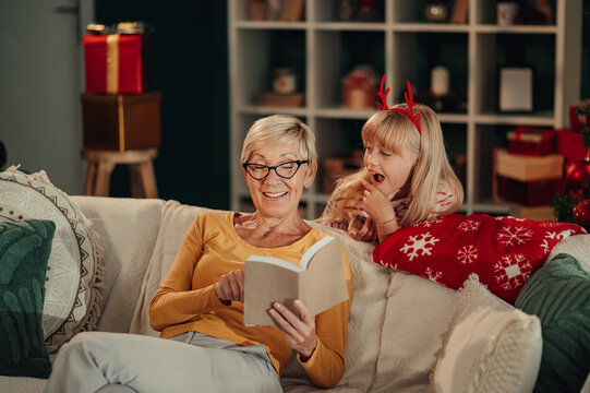 Grandmother reading christmas stories to her granddaughter on the sofa