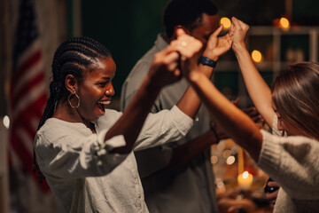 Friends holding hands and dancing together at home party