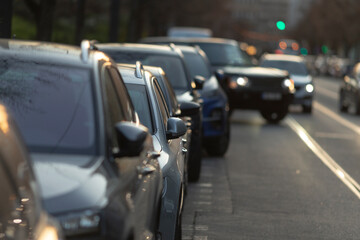 In this vibrant urban setting, rows of parked cars line the busy street, while a green traffic...