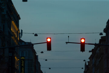 Bright red traffic lights glow in the twilight of an urban street scene, clearly signaling to vehicles that they must come to a complete stop in the busy city environment during dusk hours