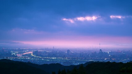 Early autumn dawn mist envelops Taipei City from Dadao Mountain. City lights fade as sunrise paints the sky.