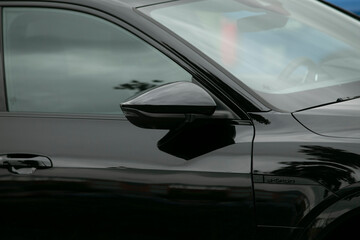 Obraz premium A sleek black car is parked in a spacious parking lot, with a blue car prominently visible in the background, adding interesting contrast