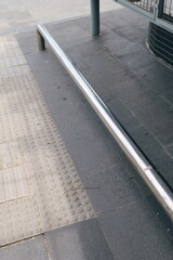 High angle view of a modern urban staircase with a stainless steel railing and tactile tiles for the blind.