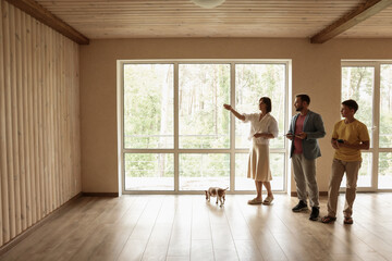 The family is planning the interior of the new home. Mom, Dad and son are inspecting and planning in the new empty room.