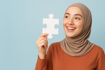 Smiling Malay Muslim woman in hijab holding puzzle piece on blue copy space
