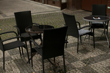 A collection of black chairs and tables arranged neatly on a charming brick sidewalk, creating a cozy outdoor seating area