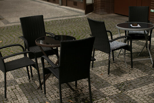 A collection of black chairs and tables arranged neatly on a charming brick sidewalk, creating a cozy outdoor seating area