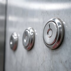Close up of three metallic buttons on a brushed metal surface one with a keyhole symbol