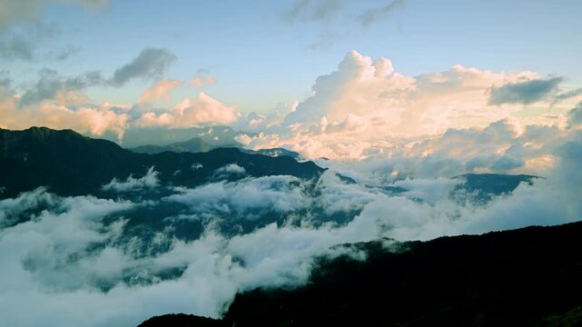 Aerial view of Hehuanshan, Renai, Nantou, Taiwan. Early autumn sun lights a winding mountain road above a sea of clouds and green slopes.