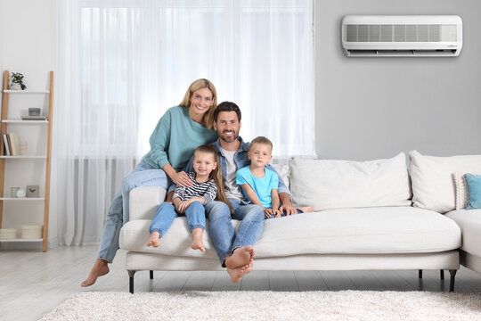 Happy family with children on sofa at home. Air conditioner keeping comfortable temperature in room