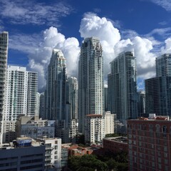 Obraz premium A city panorama showcasing towering skyscrapers against a backdrop of fluffy cumulus clouds and a clear blue sky.