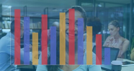 Smiling Asian woman sitting at desk in modern library, with laptop, coffee cup, bar chart overlay