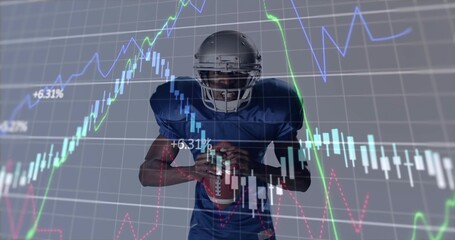 American football player in silver helmet and blue jersey holding football in studio, with charts