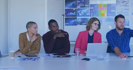 Collaborating business team analyzing charts at conference room table, with laptop tablet screens