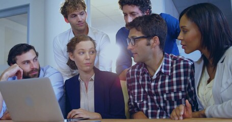 Collaborating business casual professionals typing and discussing around laptop on table in office
