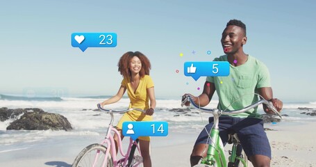 Naklejka premium Friends pedaling pink, green bikes on beach with rocky outcrops, with blue notification icons