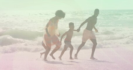 Running four-person family wearing sundress, trunks, pink swimsuit, red trunks at beach with waves