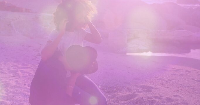 Balancing couple on sandy beach, woman wearing striped top and denim shorts, holding smartphone - Powered by Adobe