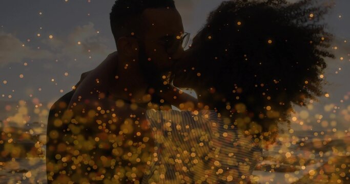 Embracing couple wearing striped top, dark shirt with eyeglasses on beach at sunset, bokeh effect