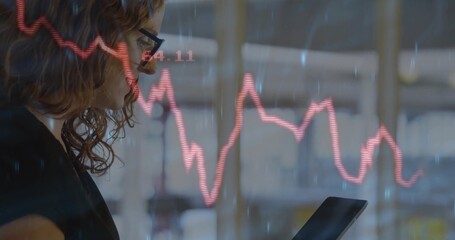 Businesswoman in dark blazer holding tablet and analyzing red graph overlay in office, copy space