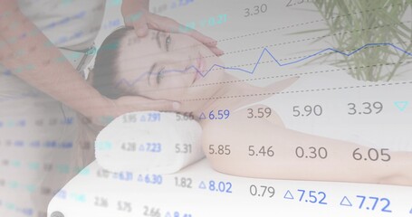 Cradling client head with massage therapist hands on table pillow, with plant and data graph