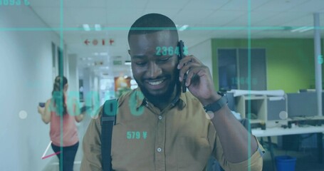 Smiling African American man talking on smartphone in office corridor, with financial data overlay
