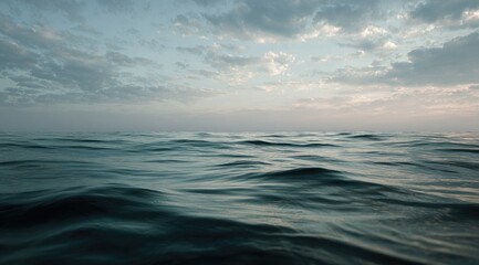 A tranquil sea at dawn or dusk.  Soft, muted colors.  Gentle waves.  Cloudy sky