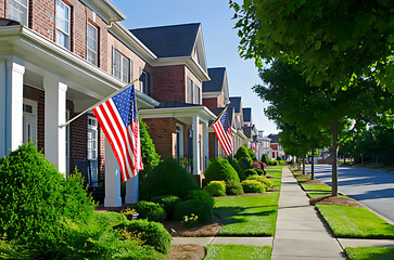 Charming suburban street lined with brick townhouses adorned with American flags and manicured green lawns on a sunny summer day offering a glimpse into peaceful residential living	