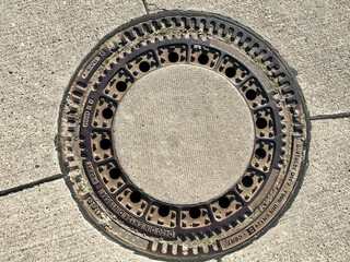 Iron hatch with a pattern above an observation well is located on auto road in daytime