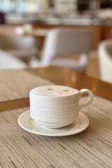 Coffee cup on saucer rests on table, surrounded by wood furniture