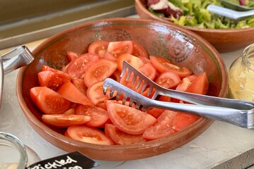 Red tomatoes cut into slices in a beautiful bowl for buffet meals in a restaurant