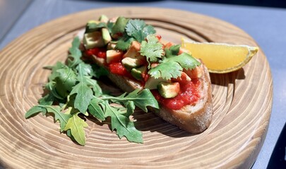 Sandwich with meat, herbs and avocado on a wooden stand in the restaurant